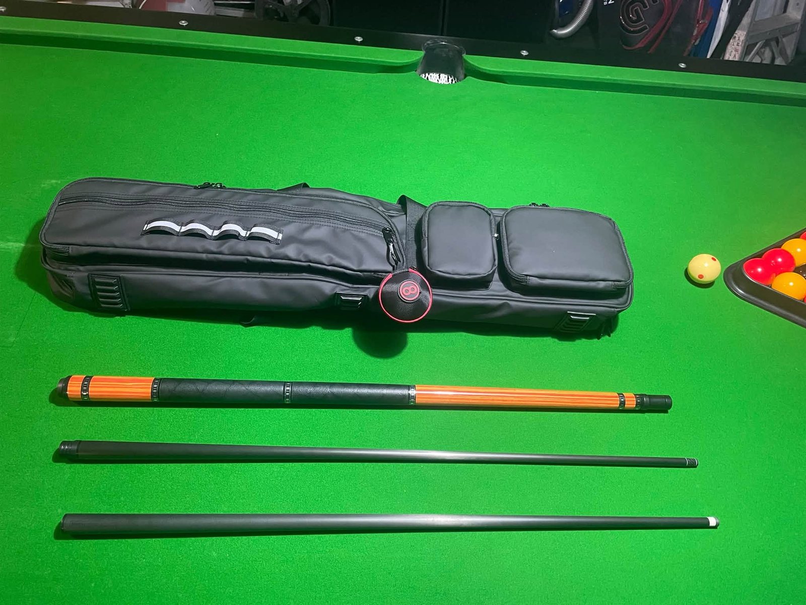 Complete cue set with carbon fibre shafts, timber butt and soft case laid out on a pool table